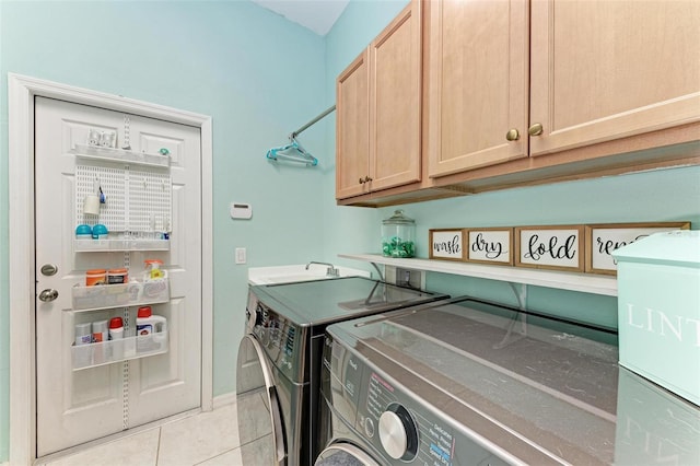 laundry area with washing machine and dryer, light tile patterned flooring, and cabinets