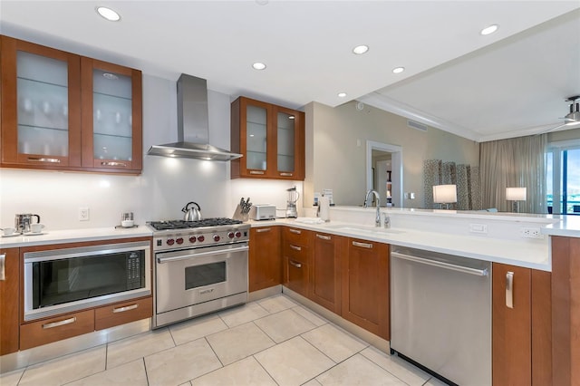 kitchen with appliances with stainless steel finishes, wall chimney exhaust hood, crown molding, sink, and light tile patterned floors