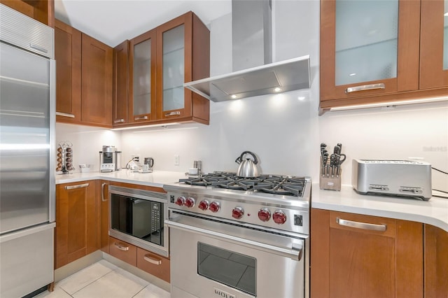 kitchen with light tile patterned floors, built in appliances, and wall chimney exhaust hood