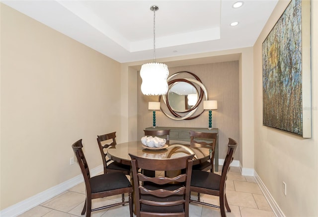 tiled dining area featuring a raised ceiling