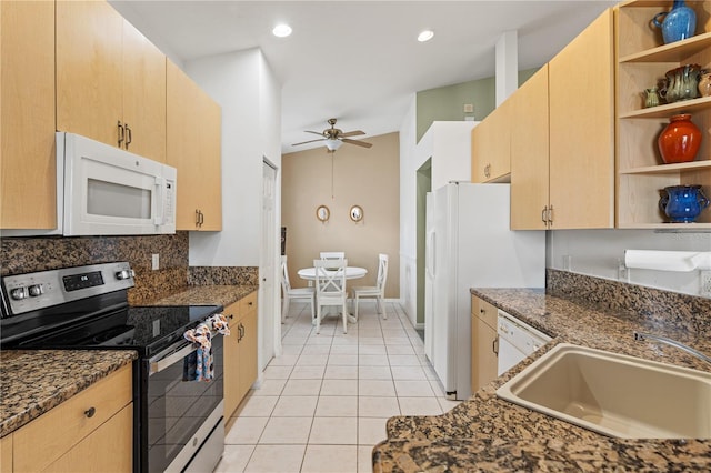 kitchen with white appliances, sink, dark stone countertops, light tile patterned floors, and light brown cabinetry