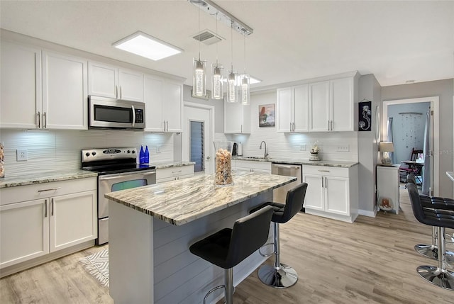 kitchen with white cabinets, stainless steel appliances, light stone counters, and tasteful backsplash