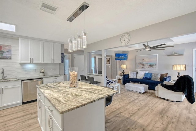 kitchen with light stone countertops, white cabinetry, sink, stainless steel dishwasher, and decorative backsplash