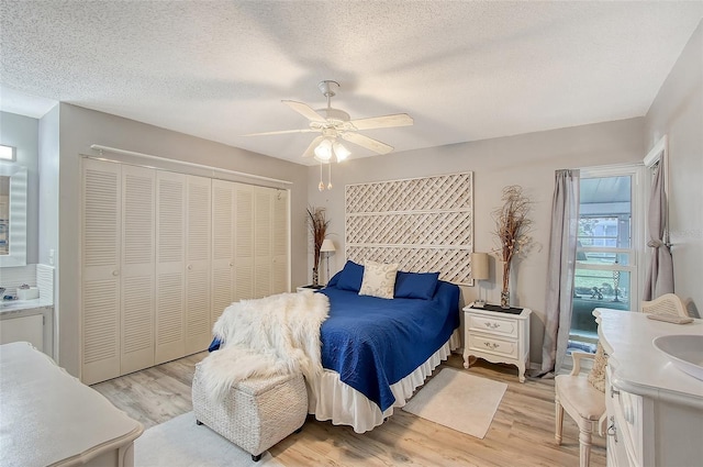 bedroom with ceiling fan, a closet, a textured ceiling, and light wood-type flooring