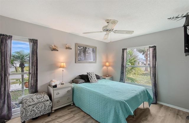 bedroom with ceiling fan, a textured ceiling, and light wood-type flooring