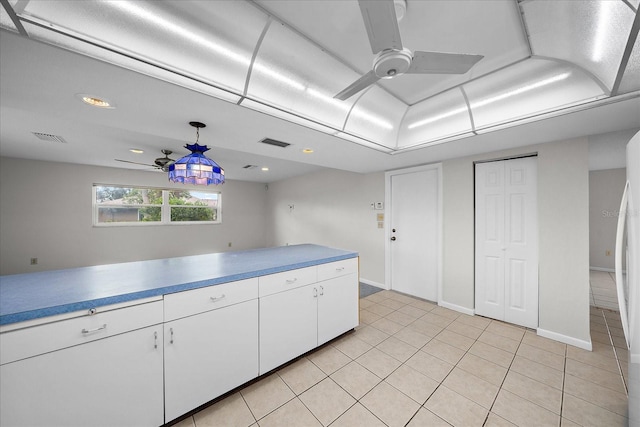 kitchen with ceiling fan, white cabinets, hanging light fixtures, and light tile patterned floors