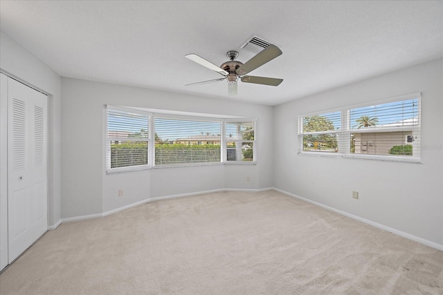 unfurnished bedroom featuring ceiling fan, a closet, and multiple windows