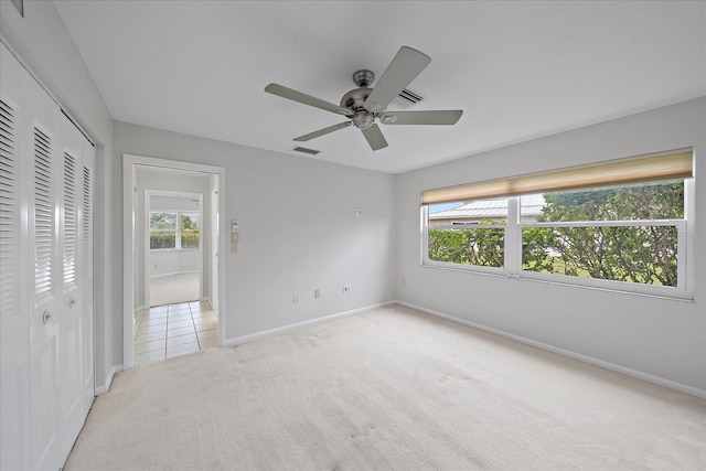 unfurnished bedroom with light carpet, a closet, and ceiling fan