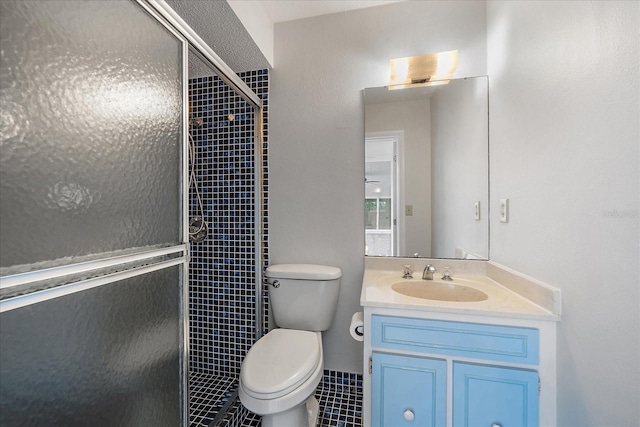 bathroom with tile patterned flooring, toilet, vanity, and walk in shower