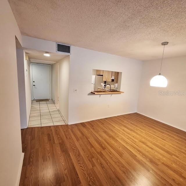 spare room with light hardwood / wood-style floors and a textured ceiling