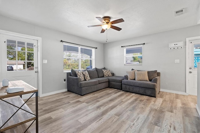 living room featuring ceiling fan, light hardwood / wood-style floors, and a textured ceiling