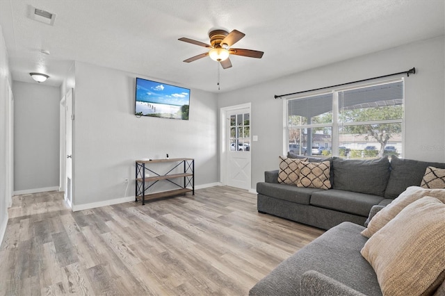 living room featuring ceiling fan, light hardwood / wood-style flooring, and a textured ceiling