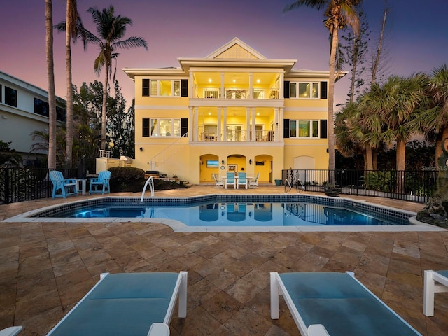 pool at dusk featuring a fenced in pool, a patio, and fence