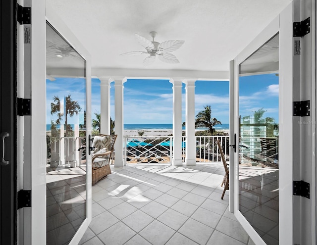 sunroom with ceiling fan and a water view