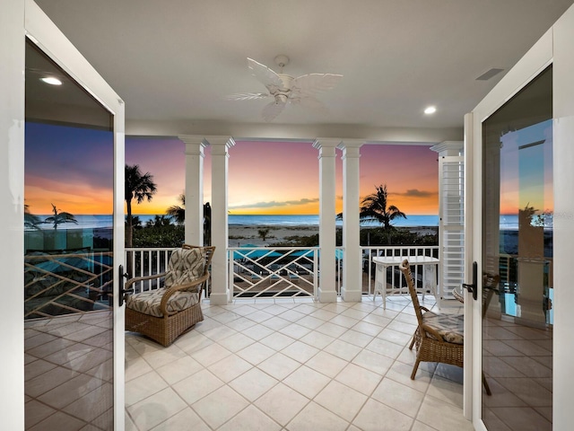 patio terrace at dusk featuring ceiling fan and a water view