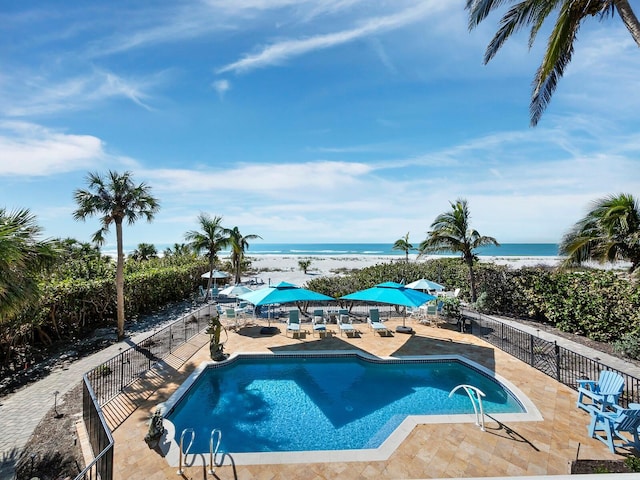 view of pool with a patio, a view of the beach, a fenced in pool, fence, and a water view