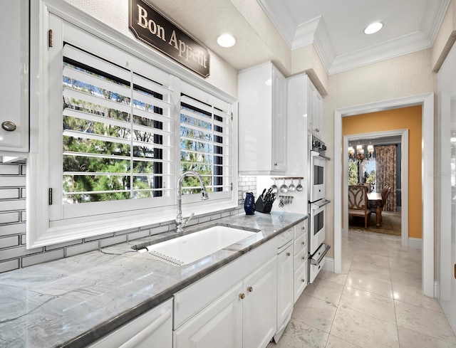 kitchen with light stone countertops, white dishwasher, white cabinetry, stainless steel double oven, and sink