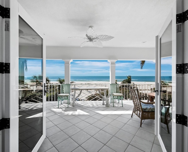 interior space with a beach view, ceiling fan, and a water view