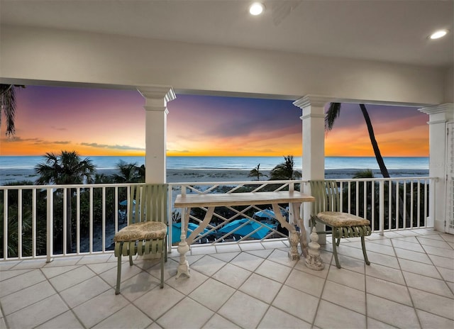 balcony at dusk with a view of the beach and a water view