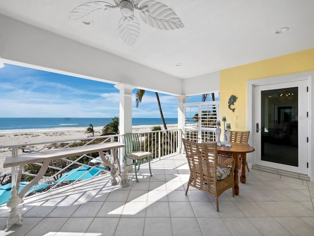 interior space with a beach view, ceiling fan, and a water view