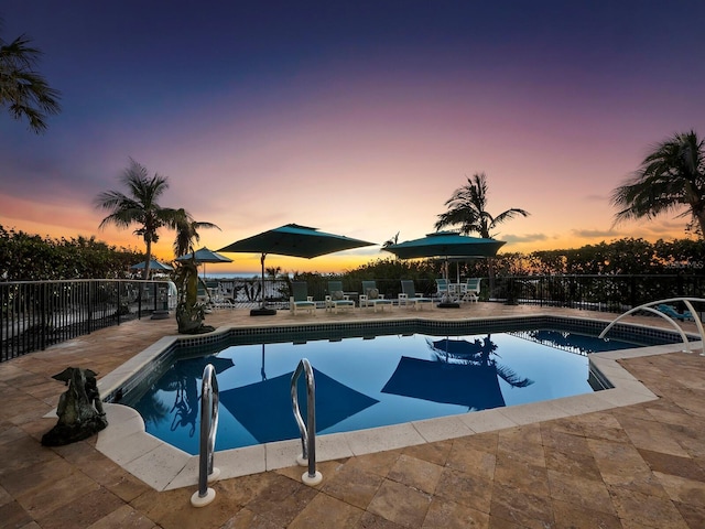 pool at dusk with a patio area