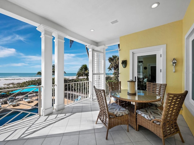 interior space featuring visible vents, a view of the beach, a water view, recessed lighting, and ornate columns