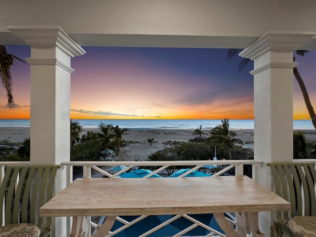 balcony at dusk with a view of the beach and a water view