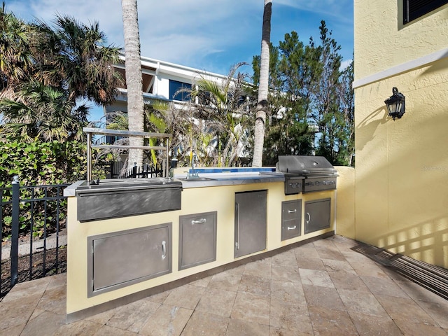 view of patio with area for grilling, fence, and a sink