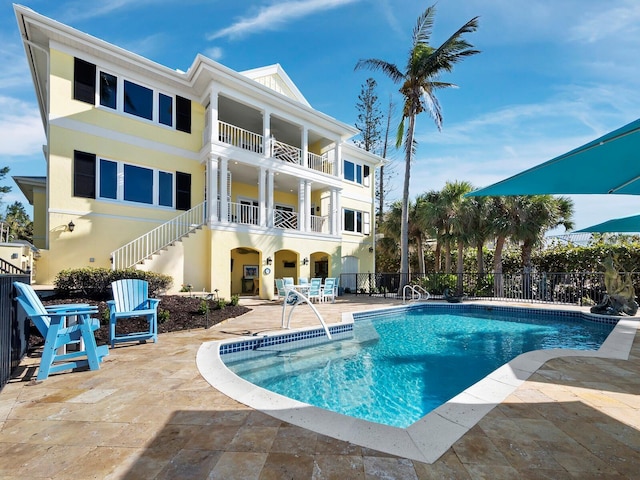 pool featuring stairway, a patio, and fence