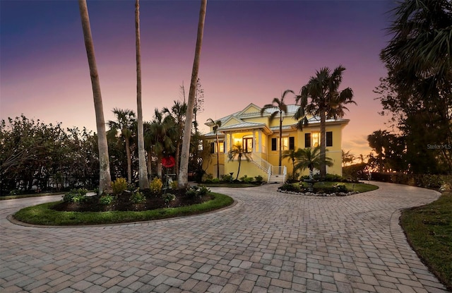 view of front of property featuring stucco siding, central AC, and curved driveway