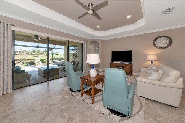 living room with a raised ceiling, crown molding, and ceiling fan