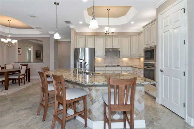 kitchen featuring a chandelier, decorative light fixtures, a tray ceiling, and stainless steel appliances