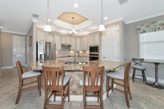 kitchen with appliances with stainless steel finishes, a kitchen breakfast bar, light stone counters, sink, and pendant lighting