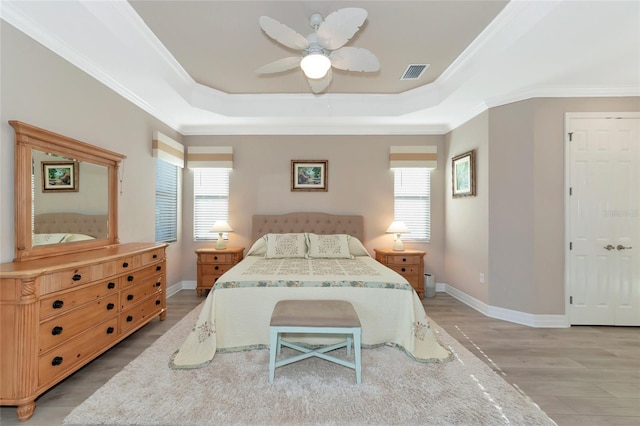 bedroom with ceiling fan, a raised ceiling, ornamental molding, and multiple windows