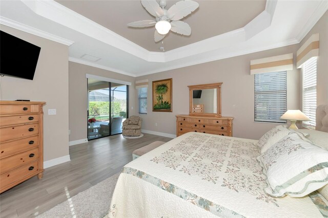 bedroom with a tray ceiling, access to exterior, ceiling fan, and ornamental molding