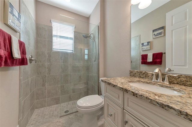 bathroom with tiled shower, tile patterned flooring, vanity, and toilet