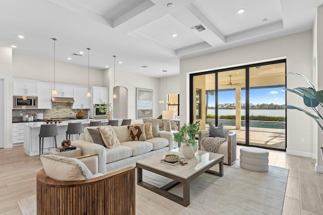 living room with ceiling fan, light hardwood / wood-style flooring, and a towering ceiling