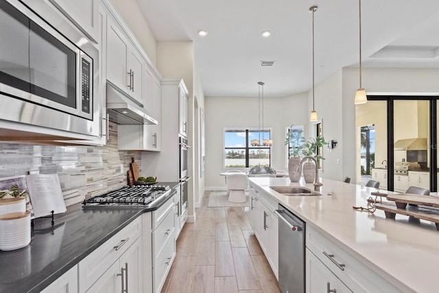 kitchen featuring appliances with stainless steel finishes, tasteful backsplash, sink, decorative light fixtures, and white cabinets