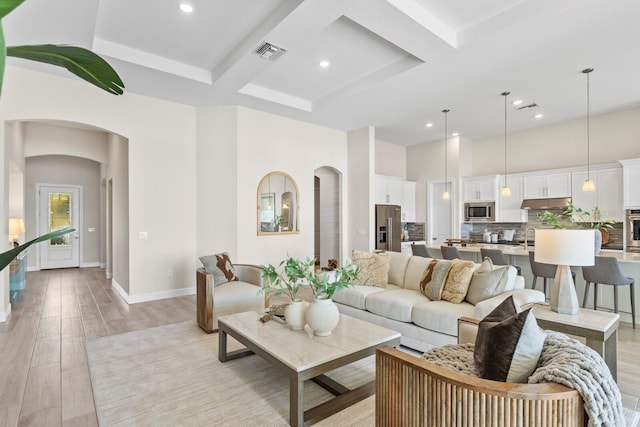 living room featuring beam ceiling, light wood-type flooring, and coffered ceiling