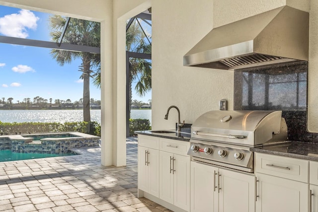 view of patio with glass enclosure, sink, a grill, area for grilling, and a water view