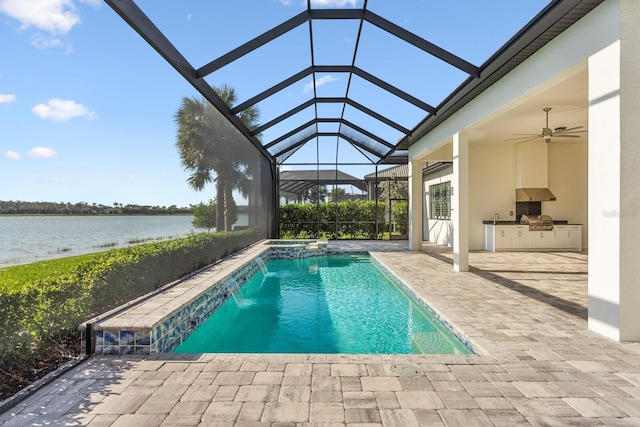 view of swimming pool featuring a water view, pool water feature, ceiling fan, exterior kitchen, and a patio