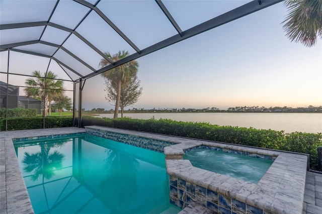 pool at dusk with a lanai, a water view, and an in ground hot tub