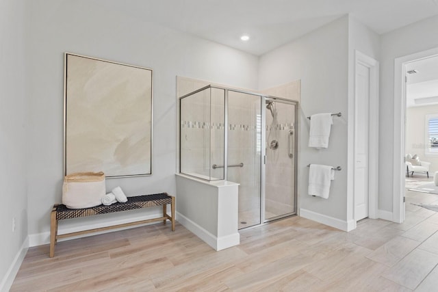 bathroom with hardwood / wood-style flooring and a shower with shower door