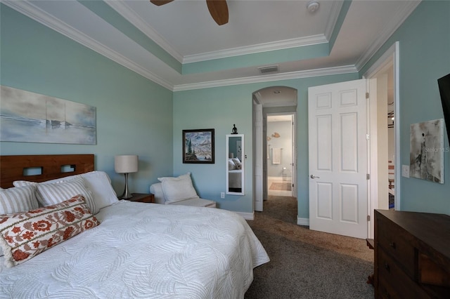 carpeted bedroom with a raised ceiling, ensuite bath, ceiling fan, and crown molding