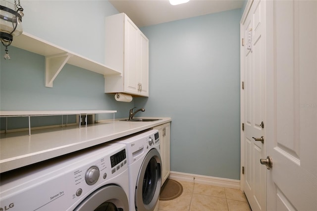 clothes washing area featuring washer and clothes dryer, sink, light tile patterned floors, and cabinets