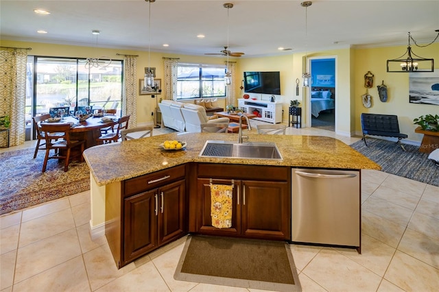 kitchen featuring pendant lighting, ceiling fan with notable chandelier, an island with sink, and sink