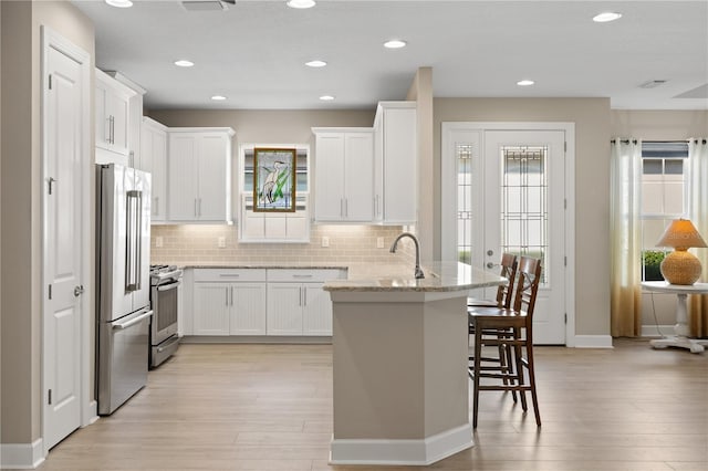 kitchen featuring light stone countertops, white cabinetry, plenty of natural light, and stainless steel appliances