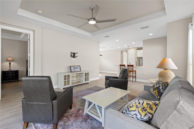 living room featuring a tray ceiling, ceiling fan, and hardwood / wood-style flooring