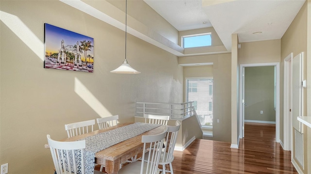 dining space with dark hardwood / wood-style flooring and a high ceiling