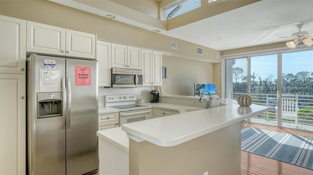 kitchen with white cabinets, plenty of natural light, kitchen peninsula, and stainless steel appliances